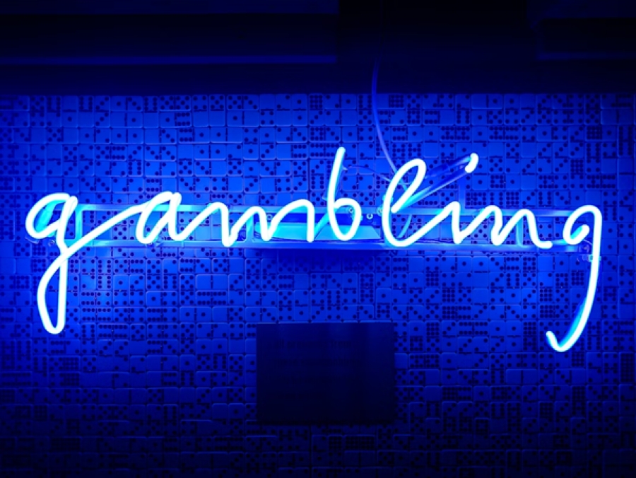 Neon sign board with vibrant blue lights displaying the word &#039;gambling&#039; in a captivating font